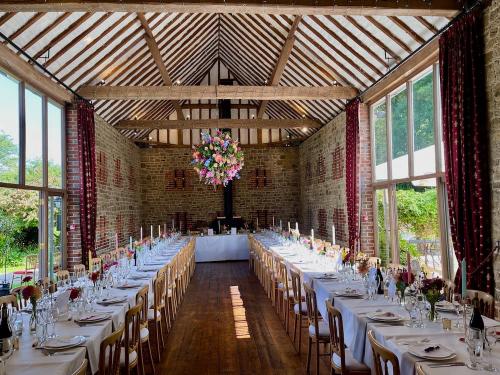 Inside view of Bartholomew Barn, a wedding venue in Kirdford, East Sussex, with dining tables ready for the wedding breakfast service