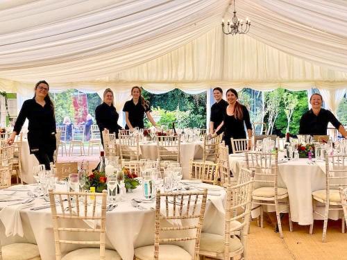 A team of six waitstaff led by our events manager Sarah Hall (far left), inside a marquee with tables dressed and ready for the wedding guests.