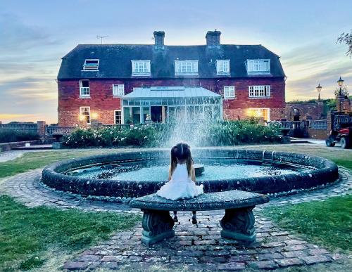 Girl watching the fountain behind the coach house, Milwards Estate, Laughton, East Sussex.