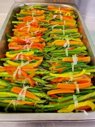 Bundles of asparagus, green beans, carrots and peppers tied with a strip of leeks.