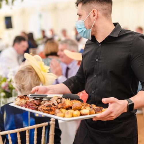 Waiter serving a sharing platter of meats and vegetables