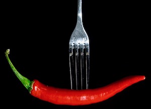Fork with a red chili on black background